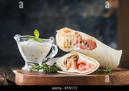 Frische Tortilla Wrap mit Gemüse und Lachs auf Holz Schneidebrett Stockfoto
