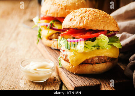 Lecker gegrilltes classic Beef Burger mit Salat und Mayonnaise Sauce auf einem rustikalen Holztisch, mit Kopie Raum Stockfoto
