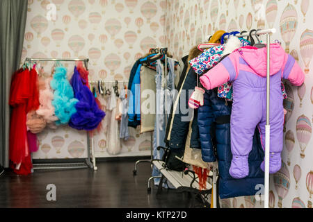 Schließen Sie verschiedene bunte Kleidung, die auf den Regalen in der Umkleide Stockfoto
