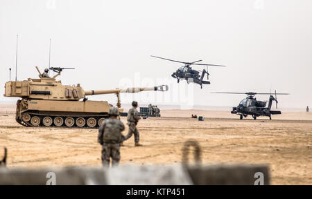 Eine AH-64 Apache ab 4. Bataillon, 227 Angriff Reconnaissance Bataillon, jetzt unter dem 42Th Combat Aviation Brigade, hebt ab, während ein M109A6 Paladin selbstfahrende Haubitze durch 3 Bataillon betrieben, 16 Field Artillery Regiment, 2. gepanzerte Brigade Combat Team, 4 Infanterie Division, trundles durch bei einem gemeinsamen Training Mission mit Jan. 15, 2014, in der Nähe von Camp Buehring, Kuwait. Der 42 CAB, New York Army National Guard, in Kuwait und hat das Kommando über Army Aviation Assets in der Region als Teil der Operation Enduring Freedom angenommen. (N.Y. Army National Guard Foto von SPC. Harley J Stockfoto