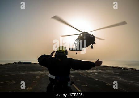 Petty Officer Ian Walker, ein Deck Hand auf die RFA Cardigan Bay, Royal Fleet Auxiliary, britische königliche Marine, gibt das Signal zum abheben, ein UH-60 medizinische Evakuierung Black Hawk von Piloten geflogen vom 1. Bataillon, 214th Air Ambulance, 42. Combat Aviation Brigade (CAB), US-Armee am 8. Juni 2014, irgendwo in den Persischen Golf.  Die Piloten ausgebildet auf Deck Landungen während Übung Spartan Kopis, einen Austausch zwischen der Cardigan Bay und die Black Hawk und AH-64 Apache Elemente der 42. Kabine, New York Army National Guard.    Spartan Kopis war das erste Mal, mit denen amerikanische Apachen eine königliche gearbeitet Stockfoto