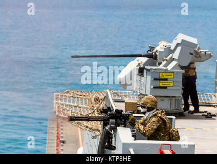 Eine königliche Marine feuert eine Mini-Pistole, als Gun crew Feuer eine 30 mm Kanone auf der RFA-Cardigan Bay, Royal Fleet Auxiliary, UK Royal Navy, während einer Live Fire Übung mit U.s.s. der U.S. Navy Thunderbolt am 10. Juni 2014, irgendwo in den Arabischen Golf. Die Cardigan Bay arbeitete mit Flugzeugen aus den 42 Combat Aviation Brigade (Kabine) während der Übung Spartan Kopis, ein Austausch zwischen der Cardigan Bay und sowohl das Black Hawk und AH-64 Apache Elemente des 42. CAB, New York Army National Guard. Spartan Kopis war das erste Mal, dass amerikanische Apachen mit einem Schiff der Royal Navy als seine Augen zu Funktion gearbeitet Stockfoto