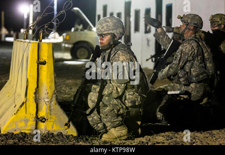 Spc. Tessa Marino (Mitte) ein Spezialist mit HHC, 42th Combat Aviation Brigade, bietet overwatch während des Angriffs ihrer Gruppe auf einer fiktiven Stadt für einen Krieger Leadership Kurs (WLC) Mission in der Nacht von 10. Juli im Camp Buehring, Kuwait 2014. Die Studenten der U.S. Army Central Command WLC geplant und LED-Missionen versus Mock gegensätzliche Kräfte über mehrere Schulungen lanes für zwei Nächte, um ihre Führung Prüfung und taktische Fähigkeiten am Ende der drei Wochen des Kurses. (N.Y. Army National Guard Foto von Sgt. Harley Jelis/Freigegeben) Stockfoto