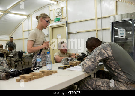 Sgt. Ashley O'Berry (links), ein Behavioral Health Sergeant, und SPC. Tessa Marino, Spezialist, beide mit HHC, 42th Combat Aviation Brigade, hören Sie eine Sendung kurz von einem Krieger Leadership Kurs (WLC) Kleingruppenleiter vor der Sendung ihre Gruppe in der Nacht vom 10. Juli 2014 im Camp Buehring, Kuwait. Die Studenten der U.S. Army Central Command WLC geplant und LED-Missionen versus Mock gegensätzliche Kräfte über mehrere Schulungen lanes für zwei Nächte, um ihre Führung Prüfung und taktische Fähigkeiten am Ende der drei Wochen des Kurses. (N.Y. Army National Guard Foto von SG Stockfoto