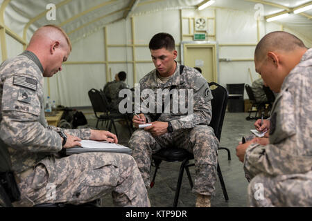 Spc. Robert Diaz, ein Hubschrauber Werkstatt mit dem 642 . Aviation Support Battalion, 42th Combat Aviation Brigade, hört auf eine Mission von Staff Sgt. Winer, ein Krieger Leadership Kurs (WLC) Kleingruppenleiter, vor der Sendung seine Gruppe in der Nacht vom 11. Juli 2014, im Camp Buehring, Kuwait. Die Studenten der U.S. Army Central Command WLC geplant und LED-Missionen versus Mock gegensätzliche Kräfte über mehrere Schulungen lanes für zwei Nächte, um ihre Führung Prüfung und taktische Fähigkeiten am Ende der drei Wochen des Kurses. (N.Y. Army National Guard Foto von Sgt. Harley Jeli Stockfoto