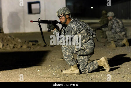 Spc. Robert Diaz, ein Hubschrauber Werkstatt mit dem 642 . Aviation Support Battalion, 42th Combat Aviation Brigade, bietet overwatch während der Angriff seiner Gruppe auf einer fiktiven Stadt für einen Krieger Leadership Kurs (WLC) Mission in der Nacht von 11. Juli im Camp Buehring, Kuwait 2014. Die Studenten der U.S. Army Central Command WLC geplant und LED-Missionen versus Mock gegensätzliche Kräfte über mehrere Schulungen lanes für zwei Nächte, um ihre Führung Prüfung und taktische Fähigkeiten am Ende der drei Wochen des Kurses. (N.Y. Army National Guard Foto von Sgt. Harley Jelis/Freigegeben) Stockfoto