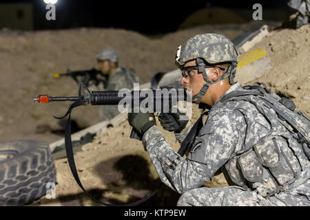 Spc. Robert Diaz, ein Hubschrauber Werkstatt mit dem 642 . Aviation Support Battalion, 42th Combat Aviation Brigade, bietet overwatch während der Angriff seiner Gruppe auf einer fiktiven Stadt für einen Krieger Leadership Kurs (WLC) Mission in der Nacht von 11. Juli im Camp Buehring, Kuwait 2014. Die Studenten der U.S. Army Central Command WLC geplant und LED-Missionen versus Mock gegensätzliche Kräfte über mehrere Schulungen lanes für zwei Nächte, um ihre Führung Prüfung und taktische Fähigkeiten am Ende der drei Wochen des Kurses. (N.Y. Army National Guard Foto von Sgt. Harley Jelis/Freigegeben) Stockfoto