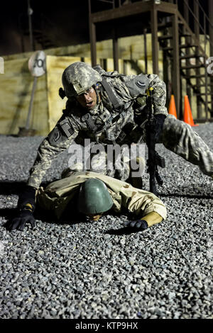 Spc. Robert Gray (Mitte), ein Arzt mit der 642 . Aviation Support Battalion, 42th Combat Aviation Brigade (CAB), und sucht Spc. Tyler Rose, eine Mannschaft Leiter mit der 42 CAB, spielen eine entgegengesetzte Kräfte Kämpfer, während ein Krieger Leadership Kurs (WLC) Training Mission in der Nacht vom 11. Juli 2014 im Camp Buehring, Kuwait. Die Studenten der U.S. Army Central Command WLC geplant und LED-Missionen versus Mock gegensätzliche Kräfte über mehrere Schulungen lanes für zwei Nächte, um ihre Führung Prüfung und taktische Fähigkeiten am Ende der drei Wochen des Kurses. (N.Y. Armee, Nation Stockfoto