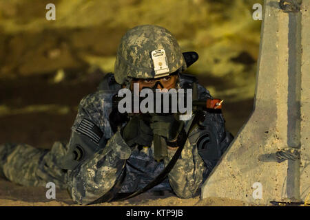 Spc. Robert Diaz, ein Hubschrauber Werkstatt mit dem 642 . Aviation Support Battalion, 42th Combat Aviation Brigade, Scans für Feinde während Angriff seiner Gruppe auf einer fiktiven Stadt für einen Krieger Leadership Kurs (WLC) Mission in der Nacht von 11. Juli im Camp Buehring, Kuwait 2014. Die Studenten der U.S. Army Central Command WLC geplant und LED-Missionen versus Mock gegensätzliche Kräfte über mehrere Schulungen lanes für zwei Nächte, um ihre Führung Prüfung und taktische Fähigkeiten am Ende der drei Wochen des Kurses. (N.Y. Army National Guard Foto von Sgt. Harley Jelis/Freigegeben) Stockfoto