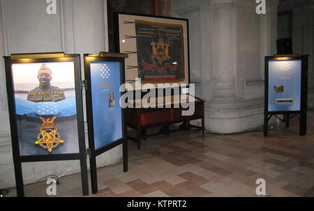 Diese Anzeige in der New York State Capitol War Room hebt die militärische Laufbahn von Sgt. Henry Johnson, an Albany New York National Guard Soldat, eine Ehrenmedaille erhalten, am 2. Juni 2015 seine heroische Welt wart ich Aktionen markieren. Johnsons Ehrenmedaille, zusammen mit einem französischen Helm wie das von Johnson und anderen Mitgliedern der 369 Infanterie Regiment, The Harlem Hellfighters, eine Armee getragen - Ausgabe bolo Messer, und ein 369 Infanterie Regiment patch, zusammen mit der Fahne des Regiments, sind auf dem Display. (Division von Militär und Marine Angelegenheiten Foto von Christopher Morton/freigegeben) Stockfoto