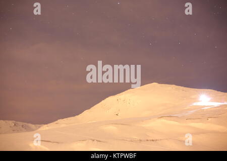 Skifahrer, die mit einem Scheinwerfer Skifahren auf einem Berg Stockfoto