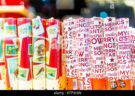 Walzen der traditionelle Weihnachten Geschenkpapier in Schrumpffolie verpackt in Rohren und auf dem Display in einem Ladengeschäft Fenster Yuletide in Großbritannien Stockfoto