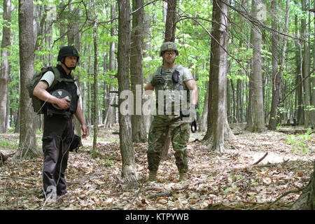 Staff Sgt. Blake Alexander der New York Army National Guard 501 Beseitigung von Explosivstoffen (EOD) Bataillon, und 1108Th EOD Unternehmen und Trevor Zigarettenkippen Büro Geltungsbereich die Chautauqua County Sheriff's, eine Hütte im Wald, die mit einer Bombendrohung während der Ausbildung 18. New York Armee Nationalgarde für eine Woche neben nationalen und internationalen EOD Militär- und Gesetzdurchführungpersonal während einer Übung namens Raven's Herausforderung an der New York State Vorbereitung Training Center in Corato New York, Mai 16-20 ausgebildet. (Foto von Sgt. J.p. Lawrence der 42th Infantry Division Stockfoto