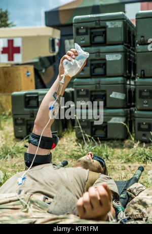 Ein Soldat von 1 Bataillon des Massachusetts Army National Guard, 182 Infanterie hält seine IV-Flüssigkeit Tasche während einer Messe Unfallversicherung Übung in der Armee Joint Readiness Training Center, Fort Polk, Louisiana, Samstag, 16. Juli 2016. Die Massachusetts 1 Bataillon, 182 Infanterie ist seit mehr als 5.000 Soldaten aus anderen staatlichen Army National Guard Einheiten, aktive Armee und der Armee finden Truppen als Teil der 27 Infantry Brigade Combat Team task force, July 9-30, 2016. U.S. Army National Guard Foto von Sgt. Harley Jelis. Stockfoto