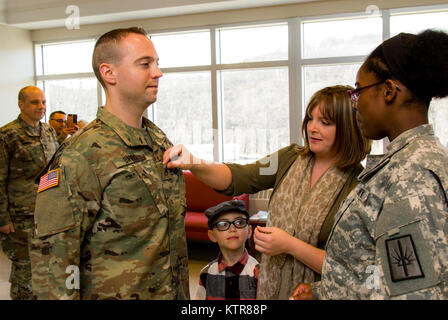 Staff Sgt. Michael Davis, 138 Öffentliche Angelegenheiten Loslösung, wird gefördert und von seiner Frau Megan Davis im Camp Smith, N.Y., Dez. 4, 2016 festgesteckt. (U.S. Army National Guard Foto von Sgt. Harley Jelis) Stockfoto