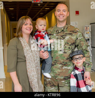 Staff Sgt. Michael Davis, 138 Öffentliche Angelegenheiten Loslösung, steht mit seiner Frau und seinen Kindern nach seiner Promotion in Camp Smith, N.Y., Dez. 4, 2016. (U.S. Army National Guard Foto von Sgt. Harley Jelis) Stockfoto