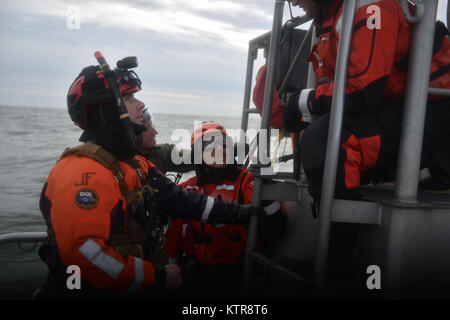 HAMPTON BAYS, NY-Flieger mit 101 Rescue Squadron und 103 Rescue Squadron Verhalten hoist Training mit United States Coastguardsmen von US Coast Guard Station Shinnecock zum 22. Dezember 2016. Während dieser Ausbildung, die Schutzengel aus der 103 RQS wurden über Hoist aus ein HH-60 Pavehawk auf das Deck des Schneidwerk abgesenkt. Danach wird das Flugzeug praktiziert Fallenlassen und Entfernen patient Würfe, vor dem Heben der Schutzengel sichern und für die Rückkehr zum Ausgangspunkt. (US Air National Guard/Staff Sergeant Christopher S. Muncy/freigegeben) Stockfoto