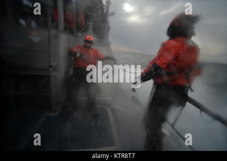 HAMPTON BAYS, NY-Küstenwache sich Klammer gegen die Seite der Cutter inmitten einer schweren Wellen während der Ausbildung in den Gewässern in der Nähe der US Coast Guard Station Shinnecock zum 22. Dezember 2016. Während dieser Ausbildung, die Schutzengel aus der 103 RQS wurden über Hoist aus ein HH-60 Pavehawk auf das Deck des Schneidwerk abgesenkt. Danach wird das Flugzeug praktiziert Fallenlassen und Entfernen patient Würfe, vor dem Heben der Schutzengel sichern und für die Rückkehr zum Ausgangspunkt. (US Air National Guard/Staff Sergeant Christopher S. Muncy/freigegeben) Stockfoto