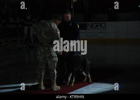 Us Army Sergeant Christopher Rodriguez, zugeordnet zu den 2. Zivile der New Yorker Nationalgarde Support Team (CST), präsentiert das Spiel puck canine Polizeihund "Ex" und Troy Polizisten Rob Smith das Rensselaer Polytechnic Institute (RPI) Hockey Spiel gegen Colgate University in Troy, NEW YORK, 3. Februar 2017 zu beginnen. Die CST Umfrage Team Soldaten waren für militärische Anerkennung Nacht in der Arena, wo RPI besiegt Colgate 5-2 präsentieren. Us National Guard Foto von Oberst Richard Goldenberg. Stockfoto