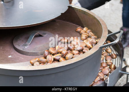 Kastanien geröstet in eisernen Pfannen über den Brand an den traditionellen Weihnachtsmarkt. Ausgewählte konzentrieren sich auf den Grill und auf der gebrannten Kastanien Stockfoto