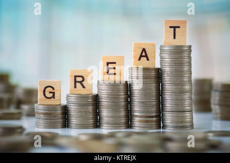 Stzck von Münzen mit Holz- Scrabble Buchstaben Stockfoto