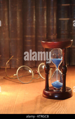 Vintage Sanduhr am Hintergrund mit alten Brillen und Bücher Stockfoto