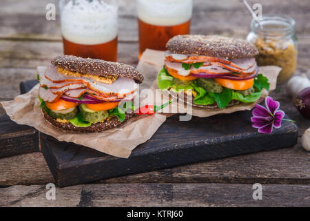 Selbstgemachtes Sandwich mit Schinken, Zwiebeln, Tomaten, Käse und mustardon rustikalen Hintergrund Stockfoto