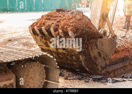 Dirty Tieflöffel Baustelle Bagger mit Graben land Boden auf Aufgabe arbeiten dig für Leitung Stockfoto