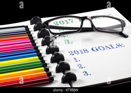 2017 Bewertungen und 2018 Ziele Text auf weißem Skizzenbuch mit Farbstift und Brillen Stockfoto