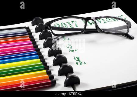 2017 Bewertungen Text auf weißem Skizzenbuch mit Farbstift und Brillen Stockfoto