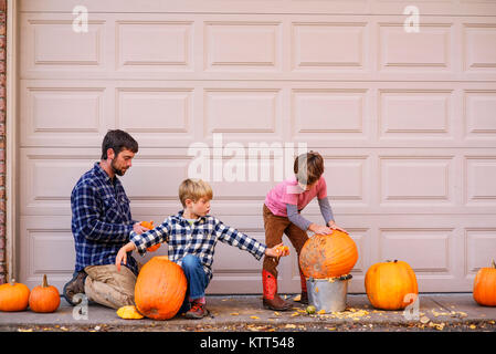 Zwei Jungs und ihr Vater schnitzen Halloween Kürbisse Stockfoto