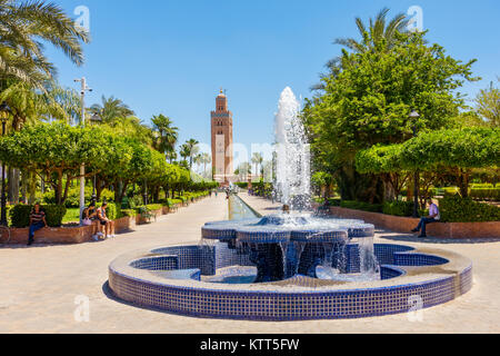 Marrakesch, Marokko - Mai 12, 2017: Die Menschen sitzen und entspannen neben dem Brunnen in der Koutoubia Gärten mit Blick auf die Koutoubia Moschee Stockfoto