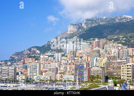 MONACO, Frankreich - Juni 28, 2017: Tageslicht zu hohen städtischen Gebäude und Werbung mit Reklametafeln. Autos fahren auf der Straße. Grüne Berge und hell blau Stockfoto