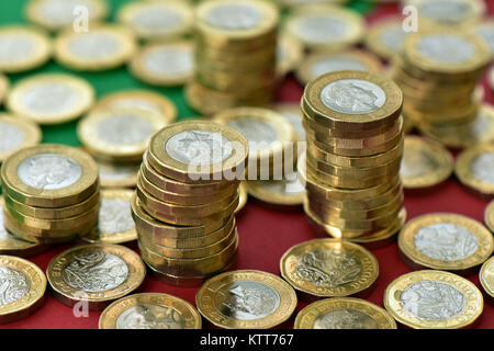 Eine große Anzahl von einem Pfund Münzen auf einer rot-grünen Hintergrund in Stapel von Bargeld. Eine Menge Geld in bar Stapel und die Stapel auf eine flache und bunte Karte Stockfoto