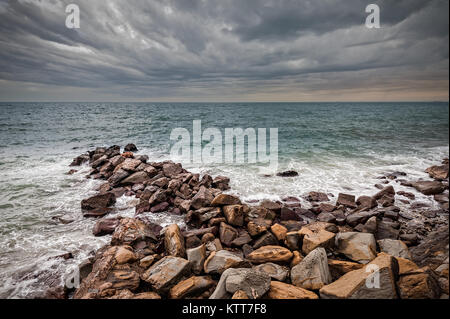 Wellen der Adria Absturz über eine künstliche Felsen unter stürmischen Himmel. Stockfoto