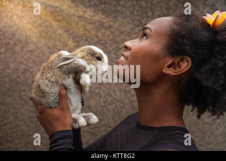 Idealistische junge afro-amerikanische Frau träumen mit Weihnachten Hase Kaninchen in Ihren Händen Stockfoto