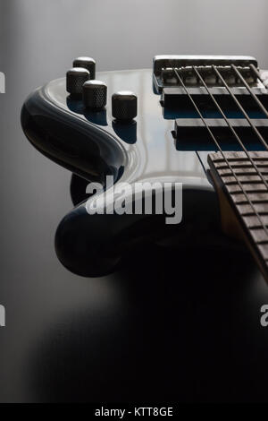 Eine blaue 5 string bass gitarre ist strategisch im Rahmen mit einem schwarzen Holz- Hintergrund positioniert. Dies ist ein dunkleres Bild, betont die sl Stockfoto