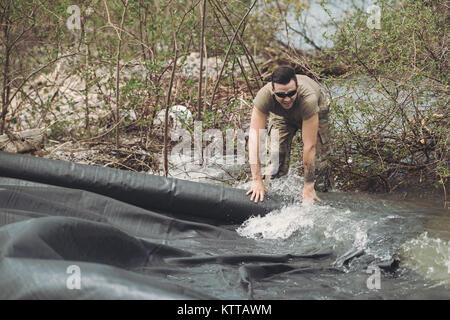 Soldaten der New York Army National Guard setup eine Plane, die eine Barriere aus Steinen und Sandsäcken, um der Erosion entlang des Lake Ontario Shoreline halten nachdem steigende Wasserstände Hochwasser und den Ausnahmezustand am 2. Mai durch reg erklärt geführt haben. Andrew Cuomo, Kendall, N.Y., 18. Mai 2017. Erodieren Küstenlinien über eine der Probleme, die sich auf Haushalte, Unternehmen und anderen Strukturen entlang des Sees, mit der New Yorker Nationalgarde Füllte mehr als 240.000 Sandsäcke diese Gemeinschaften zu schützen. (U.S. Air National Guard Foto: Staff Sgt. Stockfoto