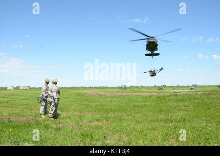 U.S. Army National Guard Soldaten vom 1. Battalion, 258Th Field Artillery zusehen, wie ein UH-60 Black Hawk Hubschrauber trägt eine M119A2 Howitzer über Fort Drum, N.Y., 8. Juni 2017. Die 258Th war die Durchführung der jährlichen Schulung der mit dem dritten Bataillon, 142 Aviation Division, die den Transport von Haubitzen beteiligt. (U.S. Army National Guard Foto von Pfc. Andrew Valenza) Stockfoto