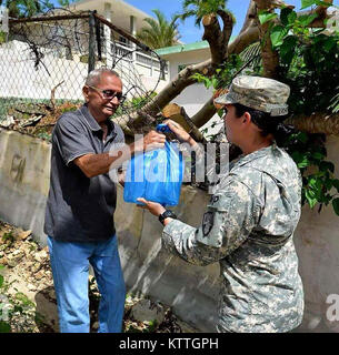 Armee Spezialist Shannon Lichten, Mitglied der 442Nd militärischen der New York Army National Guard Polizei Unternehmen bietet Wasser zu einem ein Bewohner von Barceloneta, Puerto Rico während einer Mission im Oktober. Das Unternehmen stellte über 120 Soldaten nach Puerto Rico Sicherheit Missionen im Hurrikan Maria zu führen. Der größte Teil der Einheit hat nach New York zurückgekehrt, doch 40 Freiwillige sind immer noch da. Stockfoto