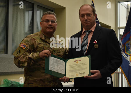 New York Army National Guard Soldat, Oberst David Martinez (links), präsentiert Master Sgt. Leonard Claus (rechts) mit der Meritorious Service Medal während seiner Pensionierung Zeremonie, in Latham, N.Y., Dez. 2, 2017. Master Sgt. Weihnachtsmann war in den Ruhestand nach 33 Jahren Service. (N.Y. Army National Guard Foto von SPC. Andrew Valenza) Stockfoto