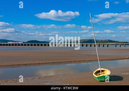 Eisenbahnbrücke am Arnside Bay. Ein kleines Fischerboot am Strand von Arnside im englischen Lake District, Großbritannien Stockfoto