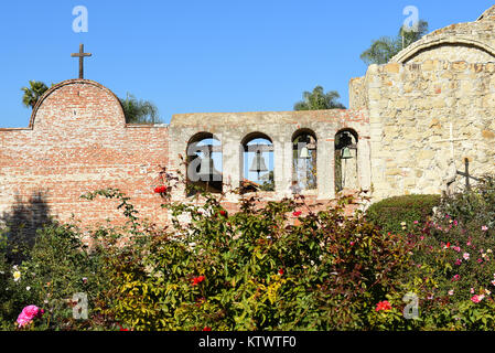 San Juan Capistrano, Ca - Dezember 1, 2017: Mission Bell Wand- und Serra Statue mit den Ruinen der großen Stein Kirche. Stockfoto