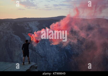 Mann die Einstellung Off Smoke Signal auf einem Felsvorsprung im Yosemite Valley Stockfoto