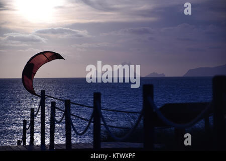 Ein kite-surfen, Segeln, Fliegen, während die Sonne auf das Mittelmeer geht mit einem bewölkten Himmel und Es Vedrà im Hintergrund Stockfoto