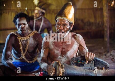 ATSY YOUW DORF, Bezirk, ASMAT REGION, IRIAN JAYA, Neuguinea, Indonesien - 23. MAI 2016: Der Mann mit der Trommel in das Haus. Mann aus dem Stamm der Asmat Stockfoto