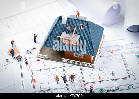 Haus Bau Projekt Konzept. Gebäude Modell und der Arbeitnehmer zu Blueprint Stockfoto