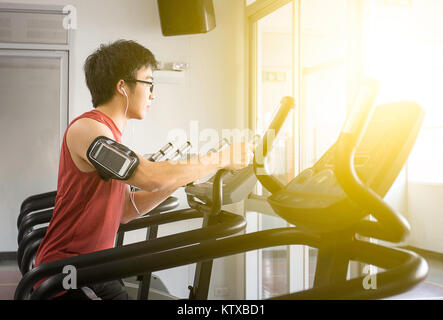 Schöner Mann auf laufende Maschine mit Musik für im Fitnessstudio entspannen, Fitnessraum Stockfoto