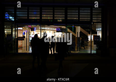 Berlin, Deutschland - 05 Dezember, 2017: die Silhouetten der Fußgänger und Wanderer vor einem Kaufhaus in der Nacht auf der Berlin Alexanderpla Stockfoto