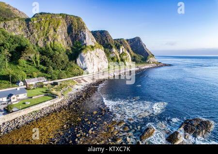 Die östliche Küste Nordirlands mit Klippen und Antrim Küstenstraße, aka Causeway Coastal Route. Luftbild bei Sonnenaufgang Stockfoto